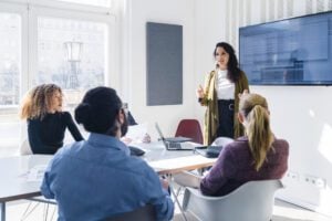 Millennial businesswoman addressing colleagues at a corporate business meeting. Group of business colleagues meeting in the boardroom.